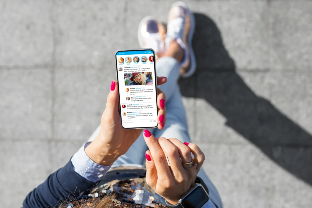 Personne utilisant un smartphone, connectée à ses reseaux sociaux, avec émojis et icônes illustrant l'engagement sur les réseaux sociaux - c'est une représentation visuelle de la stratégie de contenu digitale.