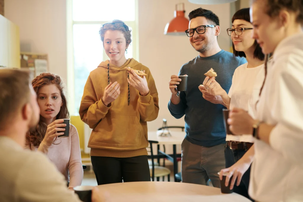 Equipe de collaborateur en pause, discutant et souriant autour d'un café, illustrant l'importance d'une bonne marque employeur et du bien-être au travail.