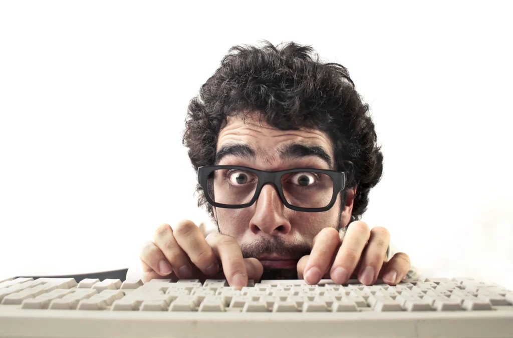 Dirigeant d'entreprise caché derrière son clavier un peu paniqué montrant l'importance de bien comprendre ce qu'est le SEO (référencement naturel)
